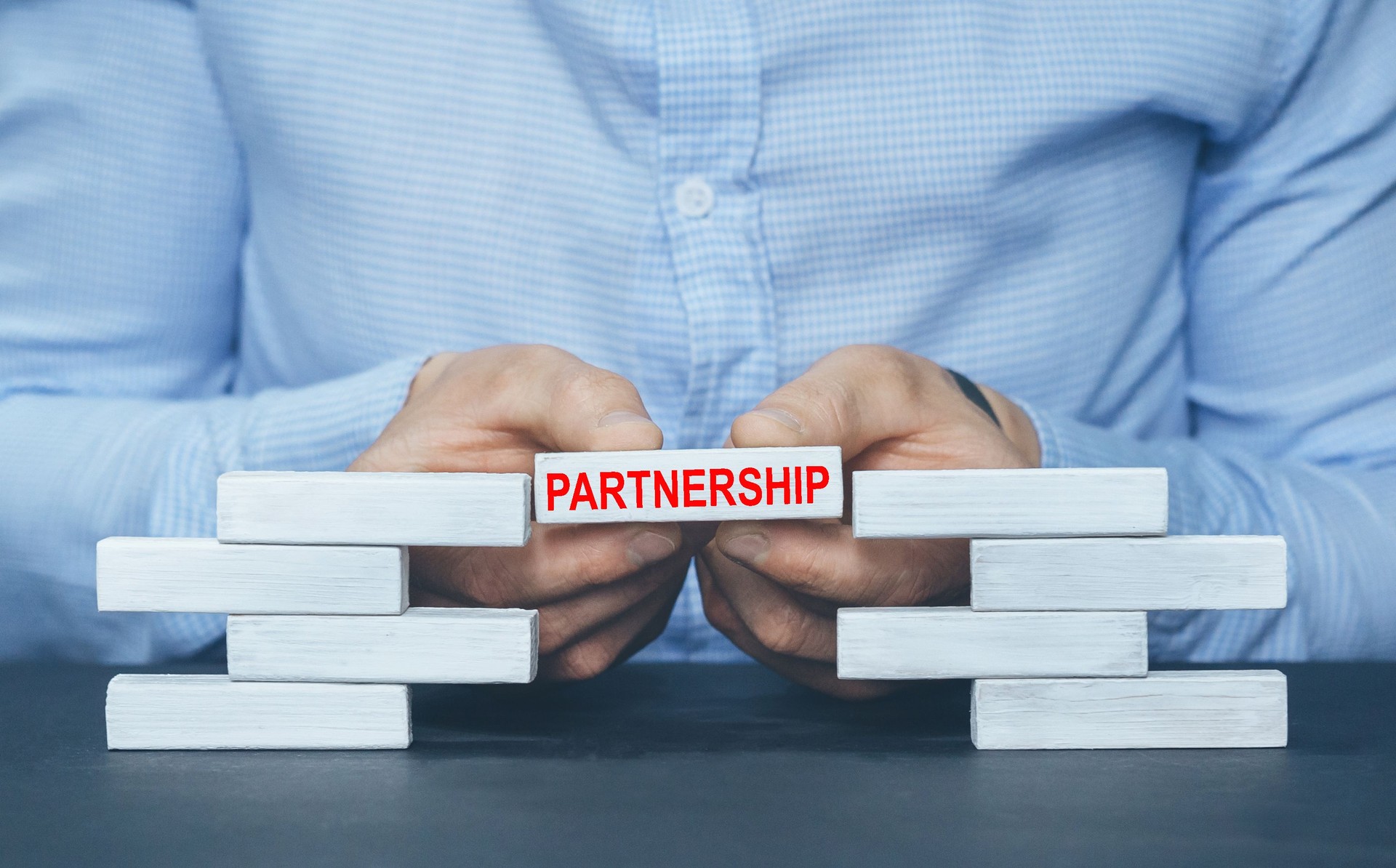 PARTNERSHIP concept. Businessman building  wooden blocks.